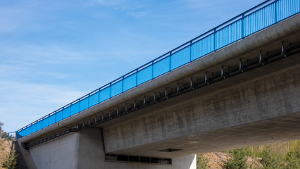 Neue Betonbrücke vor blauem Himmel und blauem Geländer