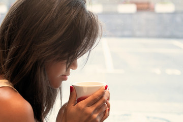 Portrait of a beautiful Asian young woman drinking a Cup of coffee. The girl in the cafe.