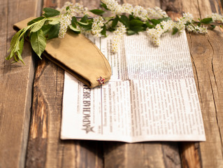 May 9 background of Victory Day. Spring flowers of cherry trees, military cap, newspaper "Red star". Wooden background.