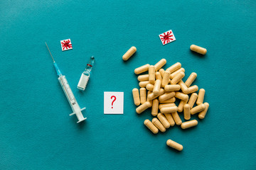 Fototapeta na wymiar Yellow pills, red question mark, medical syringe, vaccine ampoule and covid-19 icons on a blue background. Concept of counteraction to coronavirus. Flat lay, top view, copy space.