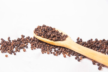 natural organic black pepper in wooden spoon