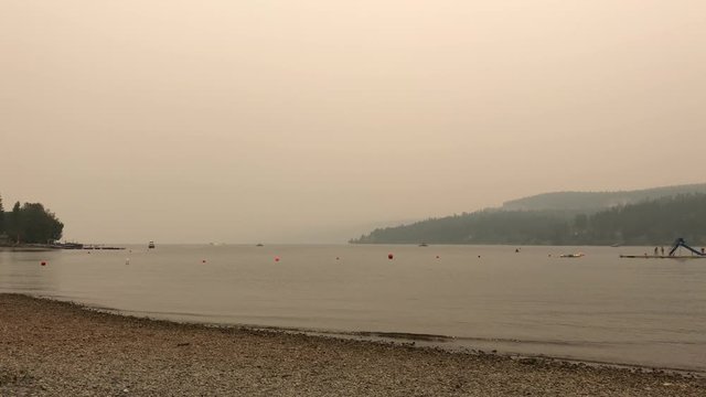 Smoke during the summer wildfire season in British Columbia over Invermere Lake, Canada. Climate change concept. 