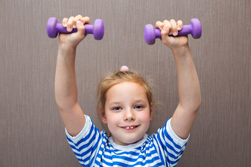 Girl child goes in for sports with dumbbells.