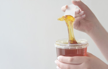  sugar paste or wax honey for hair removing flows down from waxing spatula stick.
