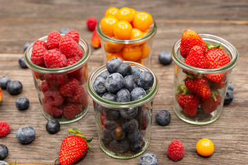 glasses with four types of berries raspberry strawberry blueberry physalis