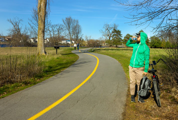 Obraz premium caucasian smiling bearded guy cyclist velo biker canadian gatineau quebec spring with a black bike on a bike route in Quebec Canada