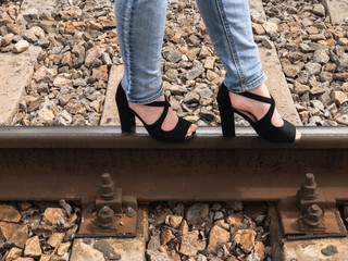 A girl walking on the rails on the high heels. Sexy legs in high heels. A girl walks on the railway. Goes towards.