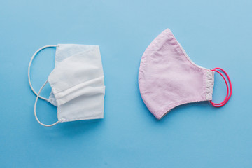 Zero waste lifestyle during virus outbreak. Reusable face mask and single use medical mask on blue background flat lay. Disposable mask and handmade textile mask