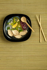 Black plate of Vietnamese Pho soup with chicken with appliances.