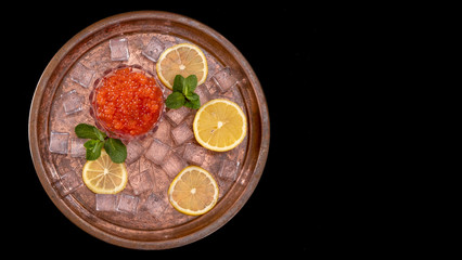 Red salmon caviar on plate with fresh lemon, ice cube, mint. Healthy diet. Selective focus Copy space Space for text