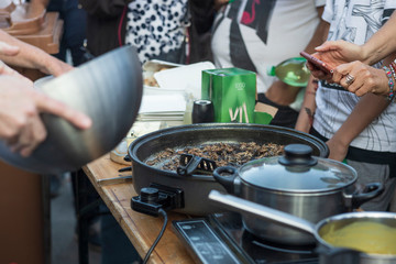 Preparing crickets in a pan for eating at a demonstration