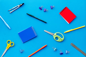 Flat lay stationery set - notebook, pen, sciccors - on blue background top view