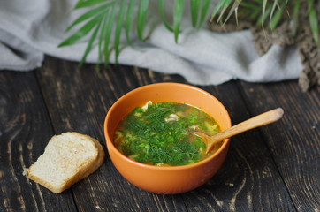 Traditional dish of vegetable soup with lots of herbs on a wooden background. Rustic style. Mouth-watering dish
