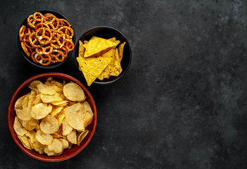 Different beer snacks, different chips and crackers on a stone background with copy space for your text.