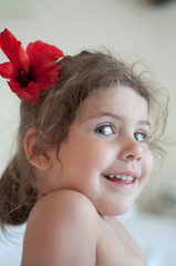 a small young lady with a huge red flower in her hair