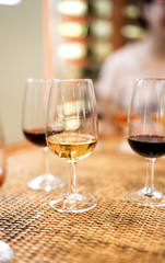 Three glasses of wine on the wooden table, closeup view on a white, red and port wines, banquet celebrating ceremony, tasting alcoholic beverages