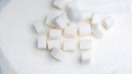 White sugar cubes fall down on granulated.