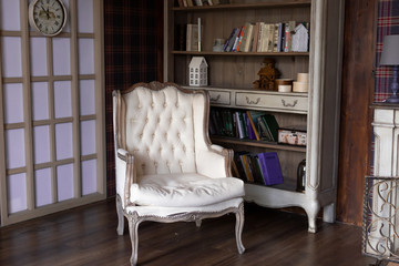 the interior of the library. classic beige leather chair next to a bookcase
