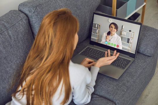 Doctor online. Young woman patient speaks with dotor online video call laptop in the living room at home.