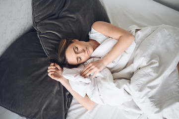 Attractive smiling young woman stretching in bed waking up alone happy concept, awake after healthy sleep in cozy comfortable bed and mattress enjoy good morning