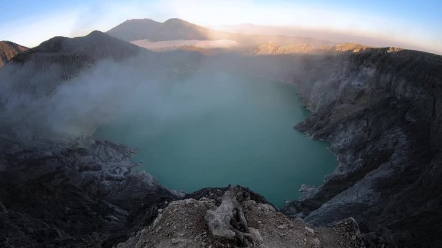 walking to the edge of the mounain with view over lake on vulcano ijen