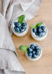 Homemade natural yogurt with granola and blueberries in glass jars on white background. Healthy breakfast set.
