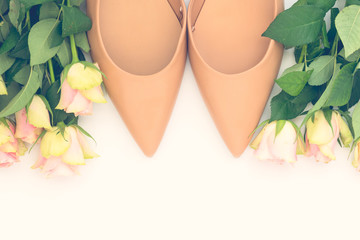 Pair of stylish pastel beige women shoes and roses on white background. Flat lay, top view trendy fashion feminine background. Beauty blog concept.