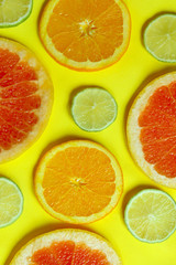 Sliced grapefruit, lime and orange are on yellow background. Colorful food background, vertical view.
