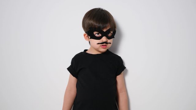 boy superhero in a black mask and with a mustache jumps in front of the camera