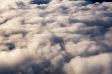 Obraz premium Aerial view from above a white and puffy clouds during a sunny sunrise. Taken from Airplane in British Columbia, Canada.