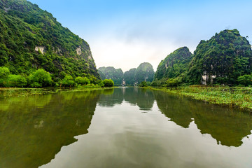 Fototapeta premium Tam Coc Natioanl Park - Vietnamese Girl traveling in boat along the Ngo Dong River at Ninh Binh Province, Trang An landscape complex, Landscape formed by karst towers and rice fields - Vietnam