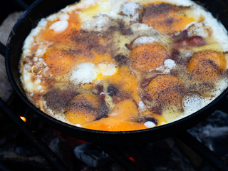 Scrambled eggs fried in a pan on a fire