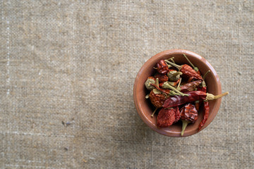 dry chilli peppers in a ceramic pot on sackcloth