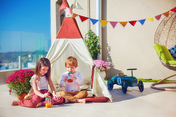 cute kids playing toys on summer patio, drinking fresh lemonade © Olesia Bilkei