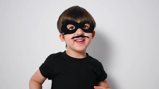 boy superhero in a black mask and with a mustache jumps in front of the camera