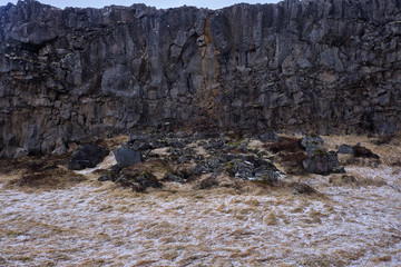 Hail covers the grass and grounds during a summer hailstorm in Iceland  on and around the boulders caused by continental drift