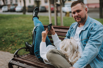 Young couple enjoying date, checking out photo session on smartphone