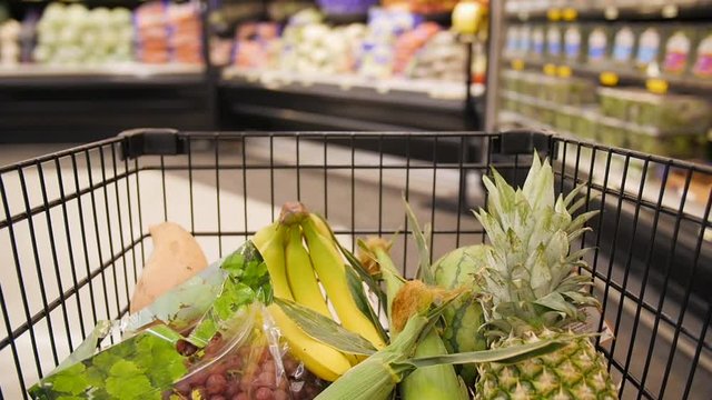 Filled Shopping Cart Moving Through Produce Isle Slow Motion.