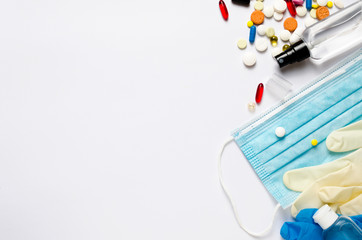 Medical mask, sanitizer bottle, pills, white white and blue medical gloves, thermometer on a white...