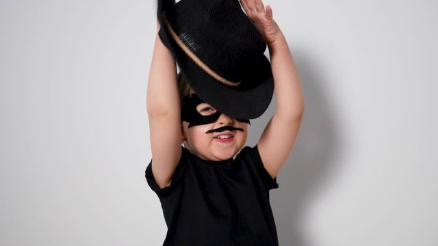 boy superhero in a black mask is trying to catch a hat flying in him