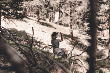 Young hipster woman travels in Colorado forest. Long dress, chelsea boots, black hat. Blonde millennial lady. Freedom. Escape home. Local traveling. Exploring places. Travel locally. Travel anxiety.