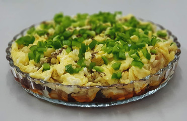 Mixed vegetables cooked and fried, on top of fried eggs, on top of small pieces of green pepper, served on a transparent plate, in the form of layers