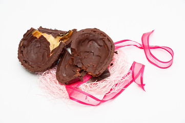Close-up of broken homemade chocolate egg with red ribbon. Celebration of Easter, Mother's Day and Valentine's Day. Isolated on white background.