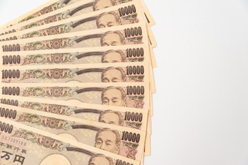 Close-up of 100,000 yen stacked in layers of 10,000 yen banknotes. Isolated on white background. Copy space. Horizontal shot.