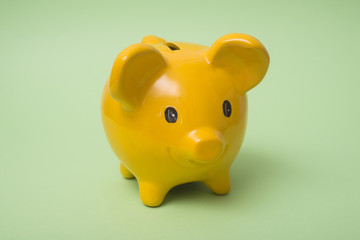 Closeup of yellow piggy bank on green background