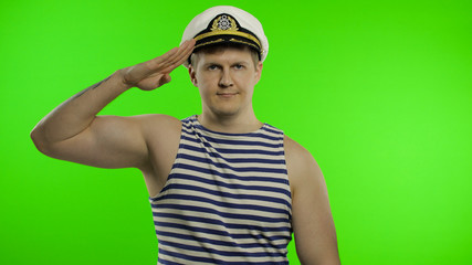 Young sailor man salutes with hand to camera. Seaman guy in sailor's vest