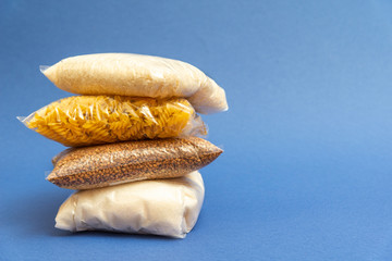 Food supplies crisis food stock for quarantine isolation period on blue. Rice, pasta, sugar, buckwheat are close up. Food delivery, donation, coronavirus.Space for text.