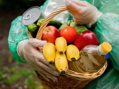 The Concept Of Volunteer Food Delivery In Bad Weather Conditions. Close-up Of A Basket Of Food In The Hands Of A Woman Volunteer.