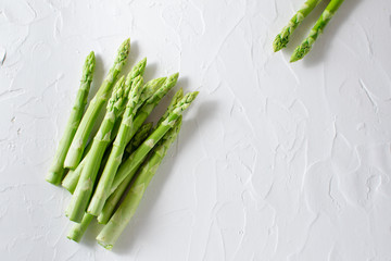 Fresh green raw asparagus on white textured background with copy space for your text. Farmers market banner. Healthy food concept.