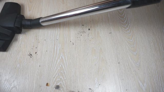 A vacuum cleaner brush removes dirt from the floor.